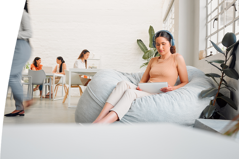 oung design student relaxing and reading or listening to music in break room in startup office, with colleagues